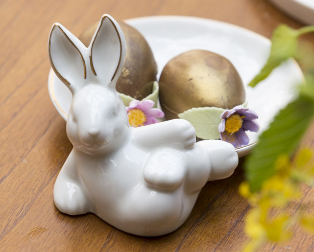 Pequenos e deliciosos ovos dourados de Páscoa em pratos de cerâmica branca 